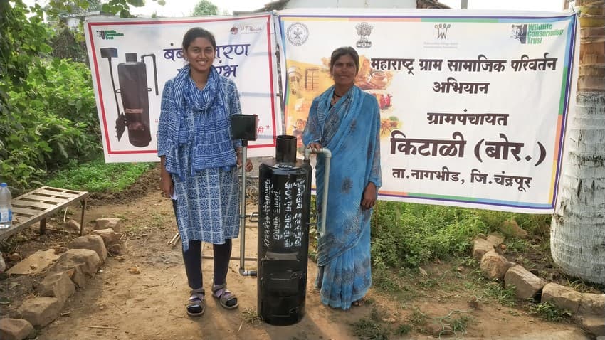 Tamanna (left) poses with a local in Kitali village, Chandrapur District, who has been provided with an independent biomass-fired water heater (bumbb) at a subsidised cost as part of the pilot project initiated by WCT.